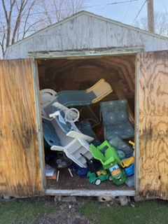 Backyard shed full of toys and debris before cleanout