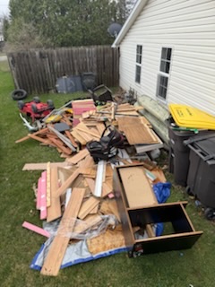 Construction and household debris pile beside house before removal